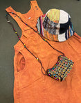 Handmade burnt orange cotton overall dress laid flat with hat and purse for styling inspiration