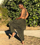 Model wearing olive green drape back drop-crotch pants outdoors with one leg up