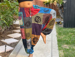 Model in patchwork harem pants with one leg raised to show drop-crotch fit