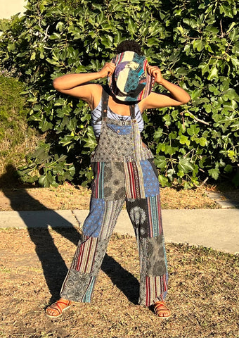Model standing in handmade patchwork cotton overalls front view styed with hat