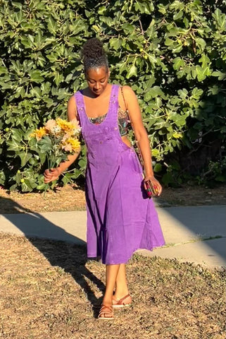 Model walking outdoors wearing purple cotton overall dress