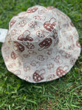 A multicolored bucket hat with a mushroom print, placed on grass against a blurred background.